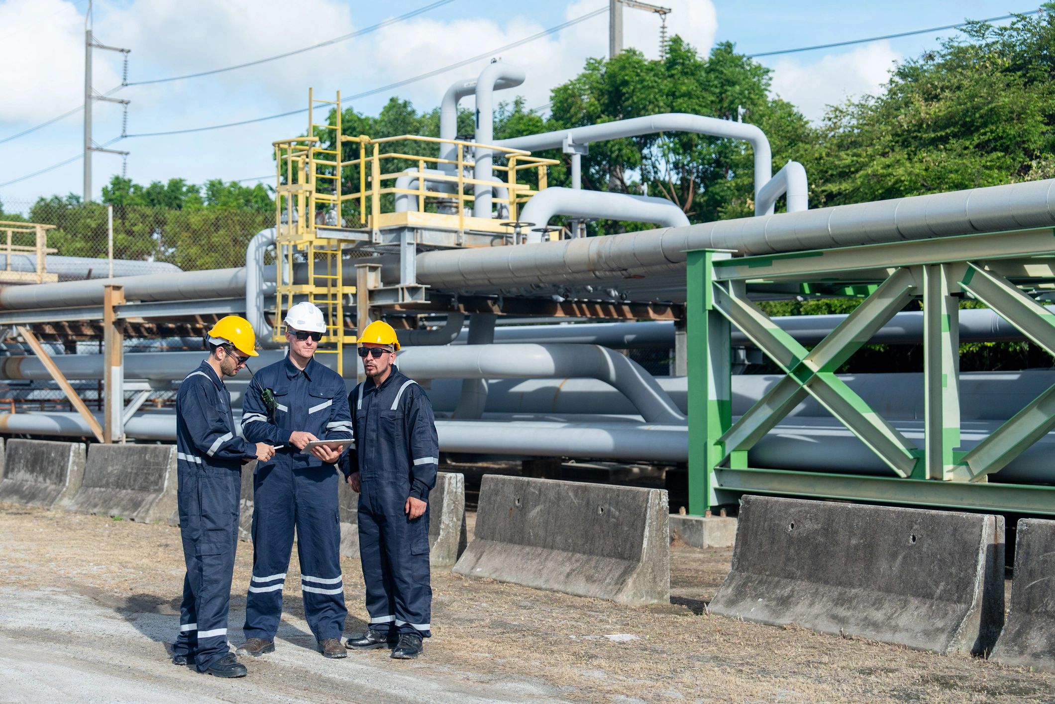 Industrial safety team reviewing work beside process piping